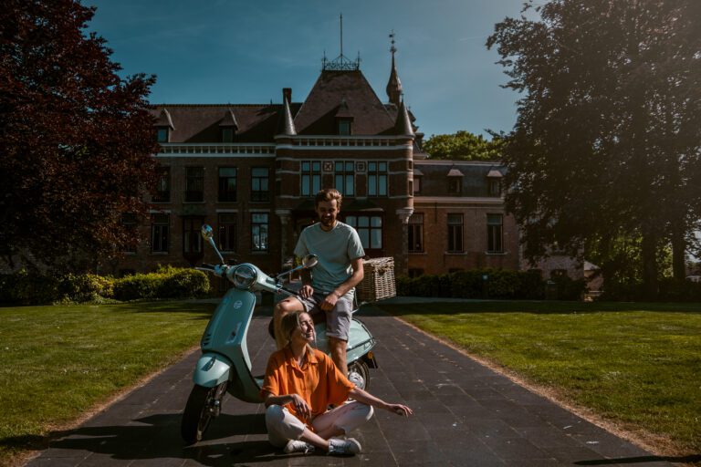 two people sitting with Vespa before nice building