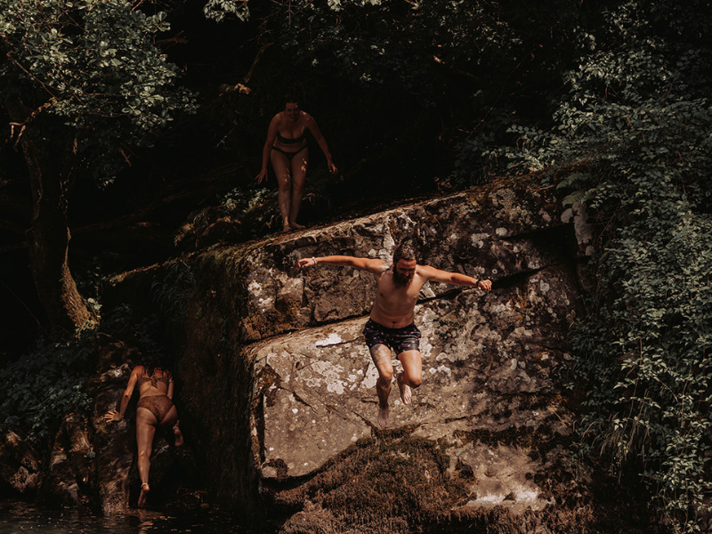 women jumping off cliff into water